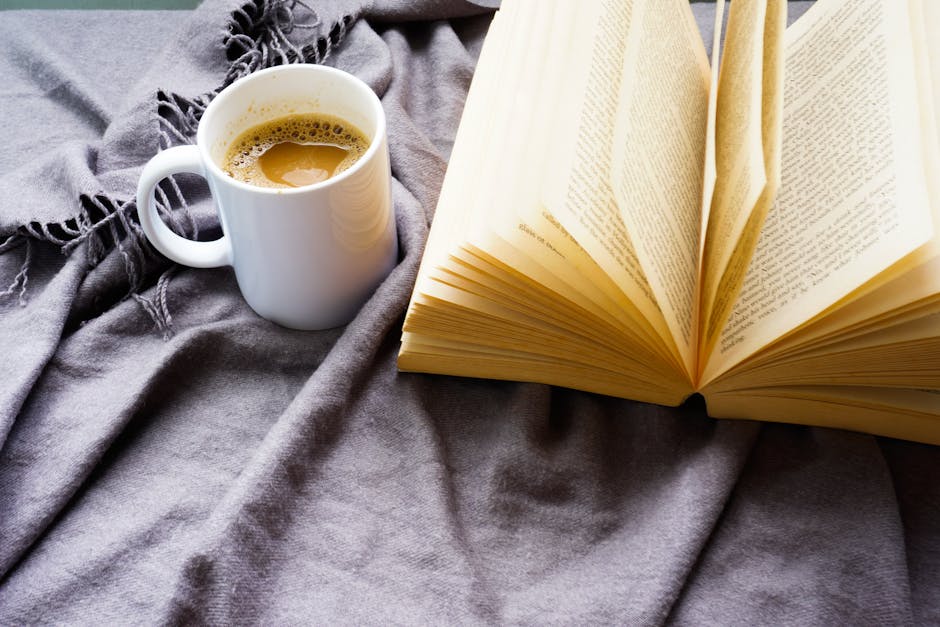 Stack of old books on table, teacup with rose-pattern and tea bag on top